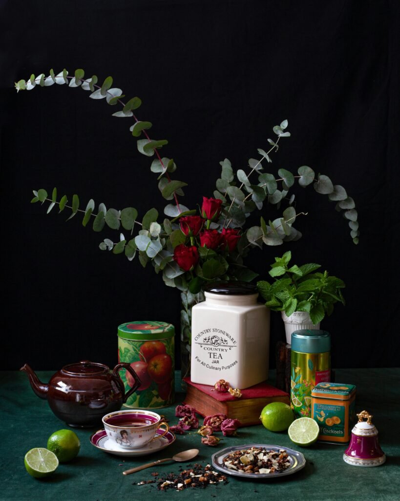 pexels-photo-10611914-10611914 Still life of a floral arrangement with roses and eucalyptus, tea, and limes on a dark background.